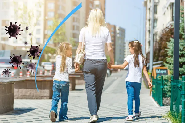 Image of a woman walking with two kids, protected by an imaginary immunity shield