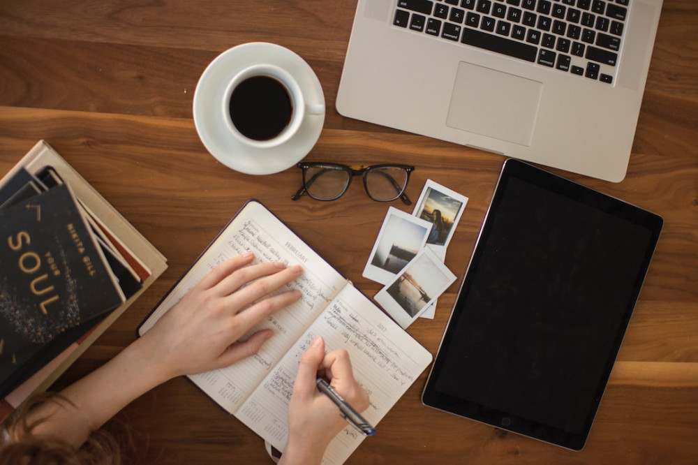 Image of a woman taking notes with a cup of coffee