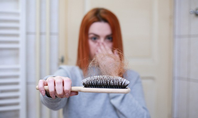 Imagen de una mujer sosteniendo un cepillo de pelo lleno de cabellos