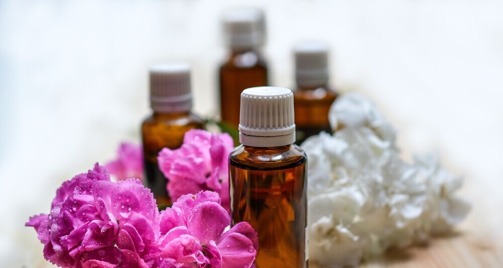 Essential oil bottles surrounded by various plants and flowers, highlighting the natural sources and benefits of essential oils.